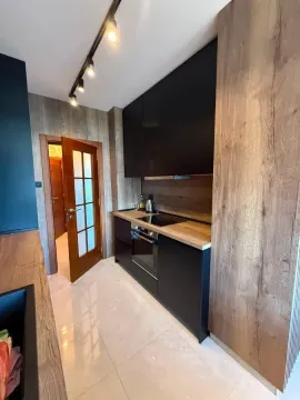 Moderna kuhinja sa tamnim elementima i drvenim detaljima. - image 6