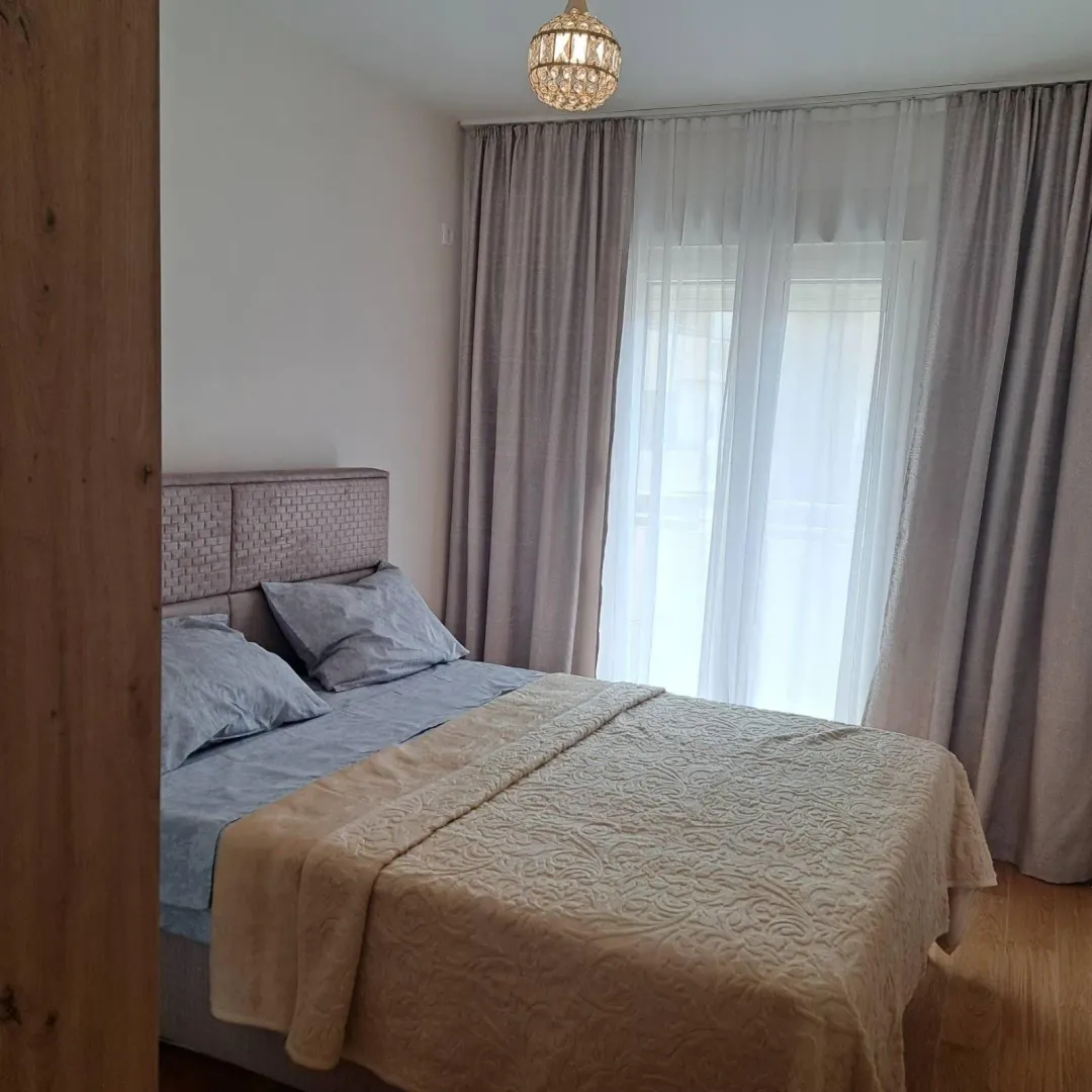 Furnished bedroom with a double bed and a window with curtains.