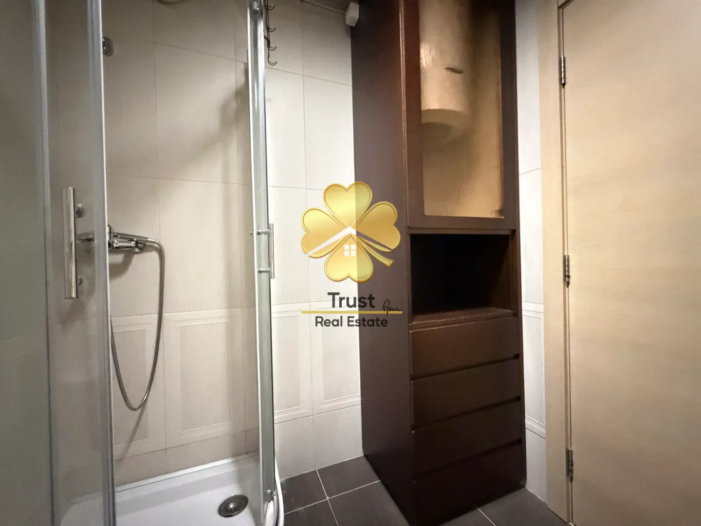 Modernly equipped bathroom with a shower cabin and a dark cabinet.