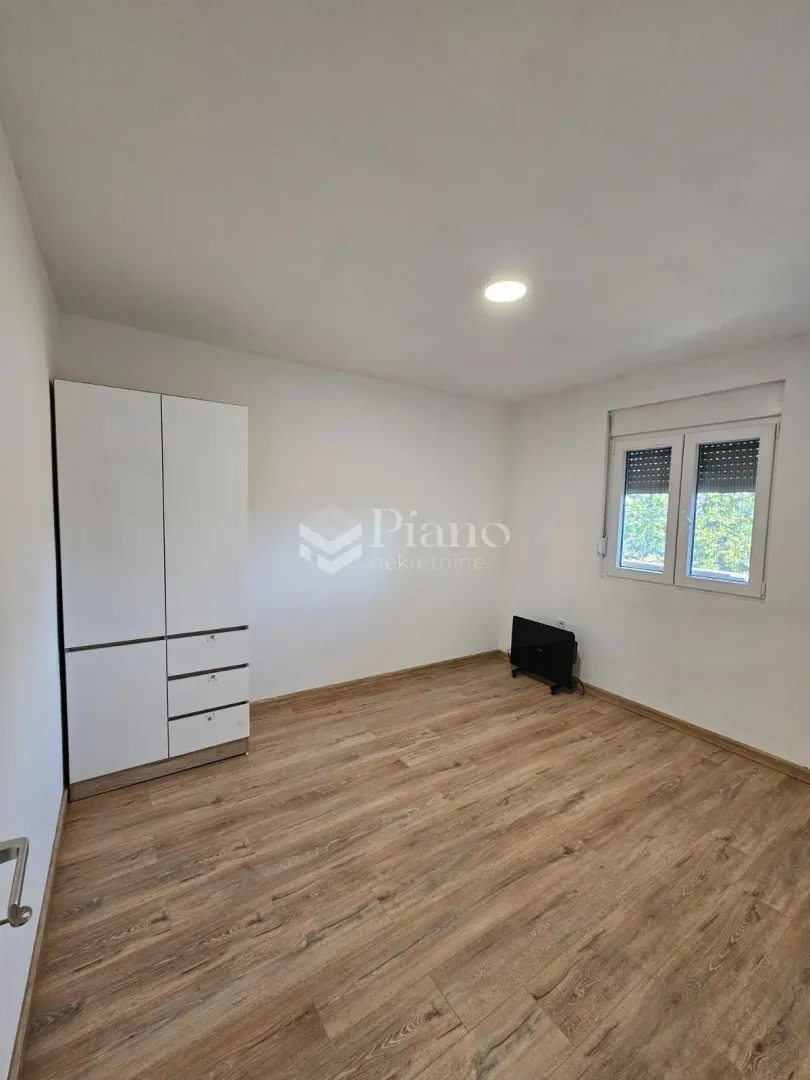 Empty room with a wardrobe, laminate flooring, and a window.