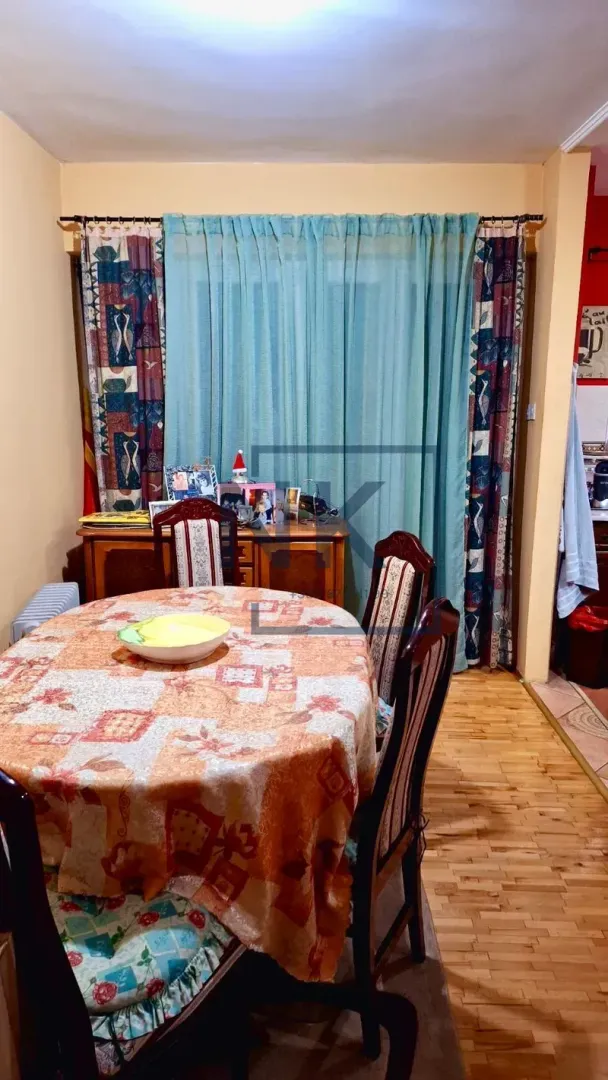 Dining area with a table, chairs, and a window covered with curtains.