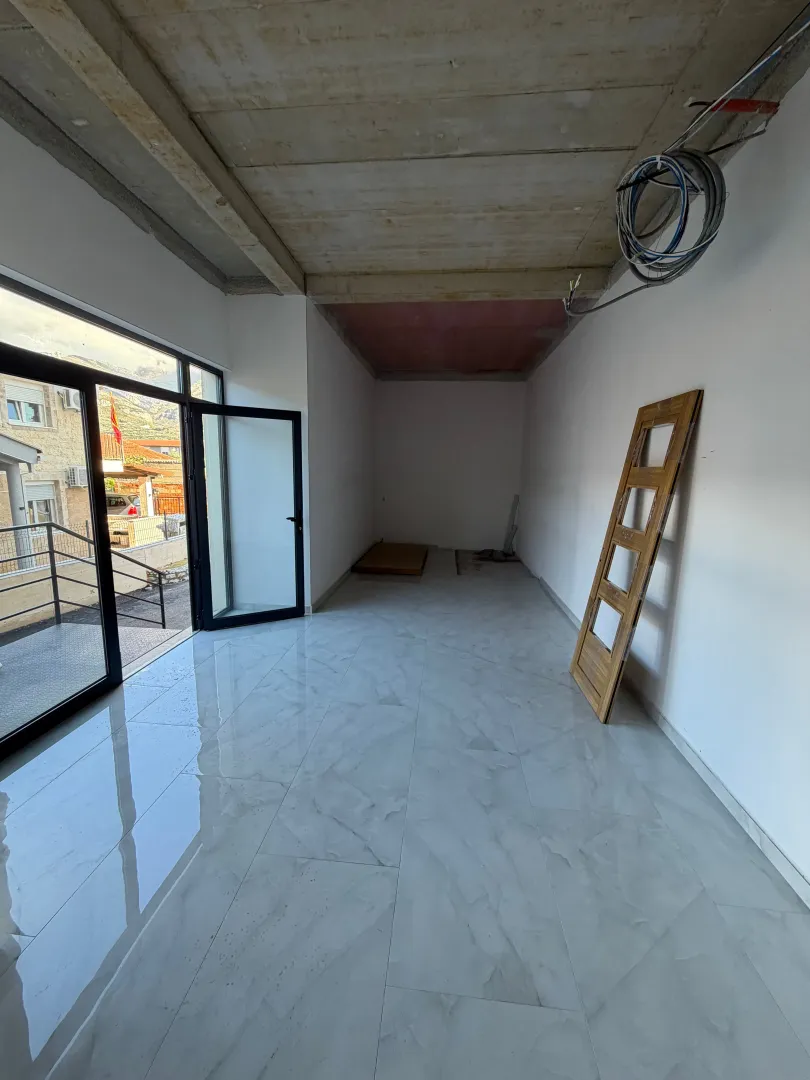 Empty room under construction with ceramic tile flooring and glass doors.