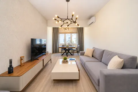 Living room with a grey sofa, TV unit, and dining area in the background. - image 16