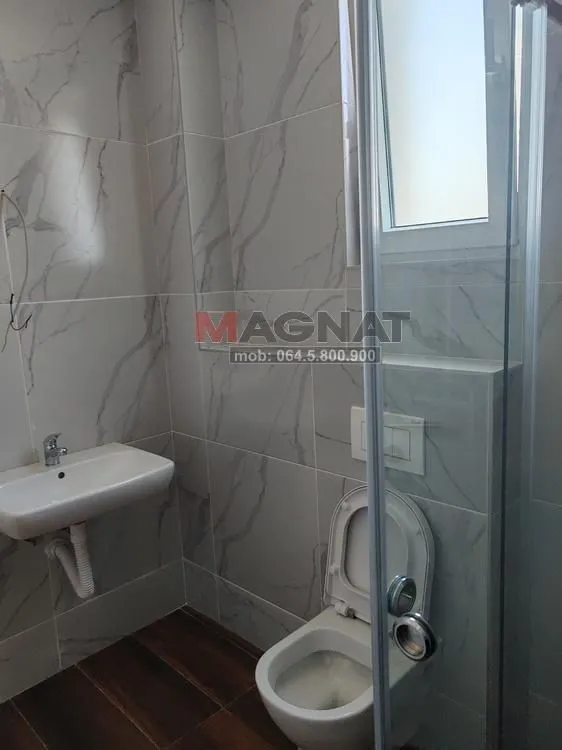 Kupatilo obloženo keramičkim pločicama sa umivaonikom, WC šoljom i tuš kabinom.
