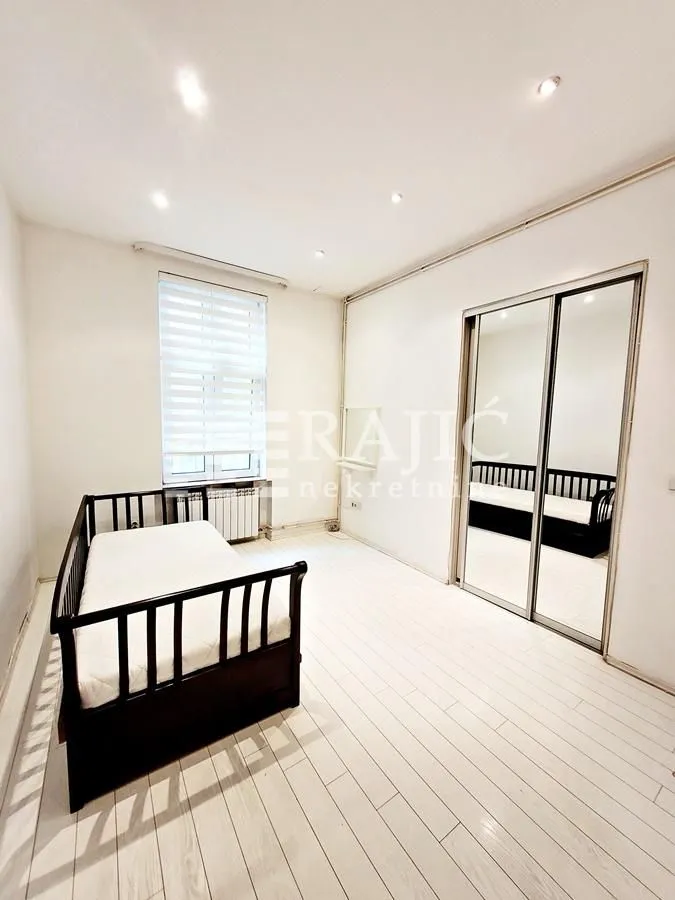 Bright bedroom with a bed and a built-in mirrored wardrobe.
