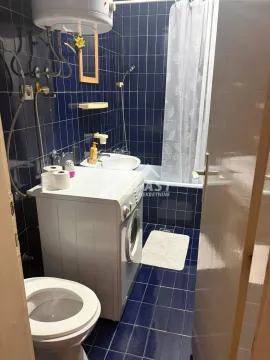 Manje kupatilo obloženo plavim pločicama sa kadom, umivaonikom, wc šoljom i veš mašinom. - image 17