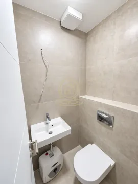 Manje kupatilo obloženo bež pločicama sa umivaonikom i toalet šoljom. - image 11