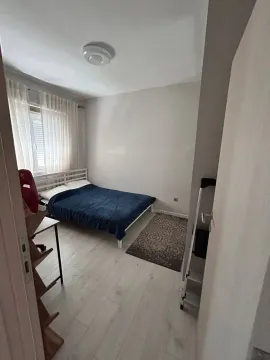 Manja spavaća soba sa krevetom, bijelim podom i prozorom sa zavjesama. - image 4