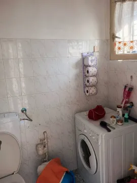 Kupatilo sa toaletom, veš mašinom i bijelim keramičkim pločicama na zidovima. - image 5