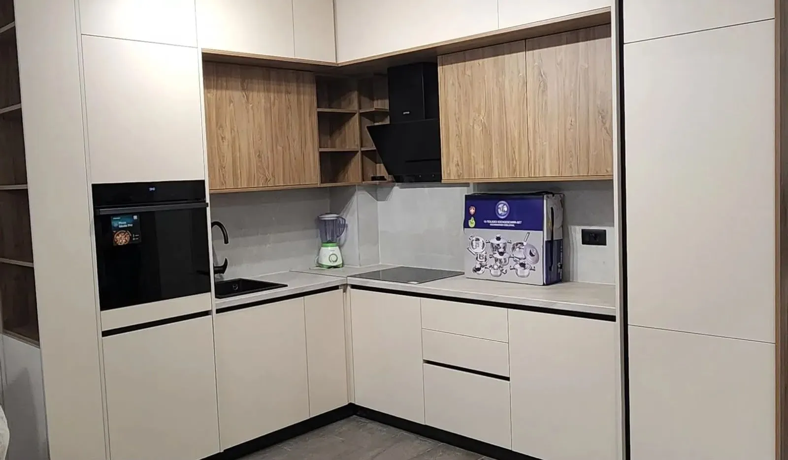 Modern corner kitchen with built-in appliances and white fronts.