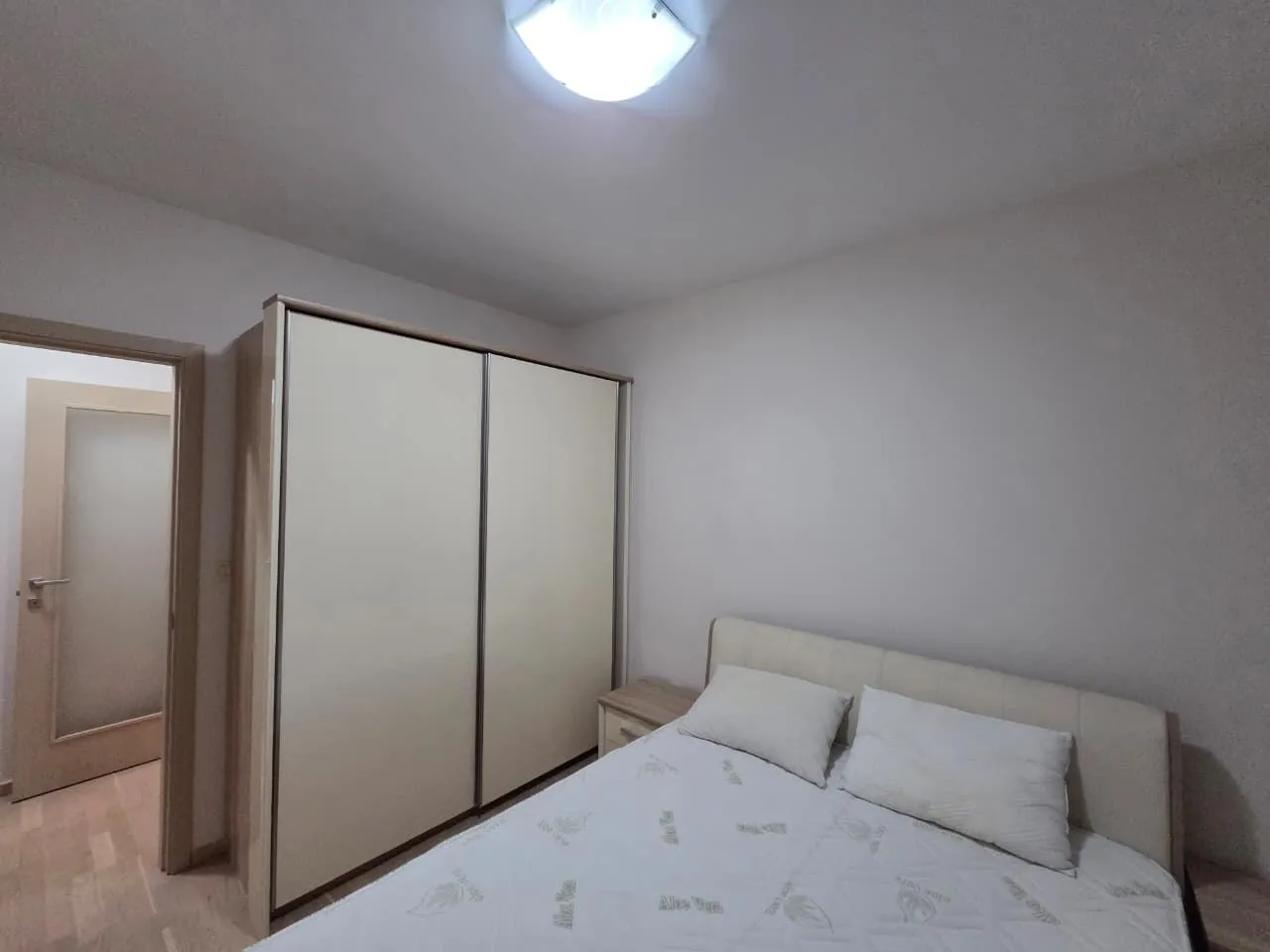 Furnished bedroom with a double bed and a large wardrobe.
