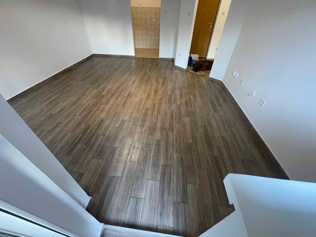 Empty living room with wood flooring.