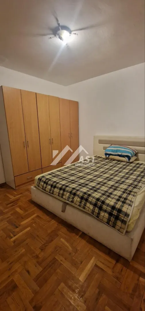 Spavaća soba sa bračnim krevetom i drvenim ormarom.