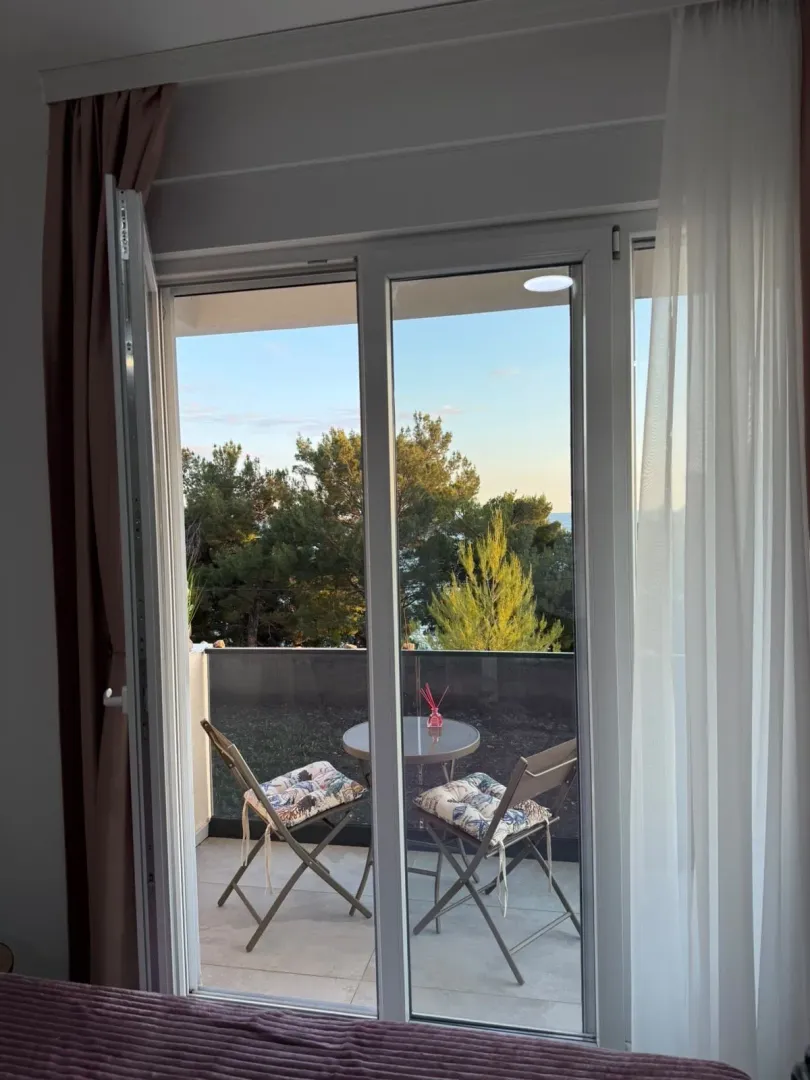 View through the balcony doors onto a terrace with patio furniture.