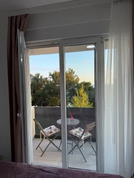 View through the balcony doors onto a terrace with patio furniture. - image 7