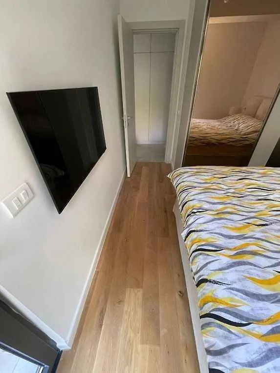 Spavaća soba sa bračnim krevetom i zidnim televizorom.