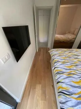 Spavaća soba sa bračnim krevetom i zidnim televizorom. - image 8