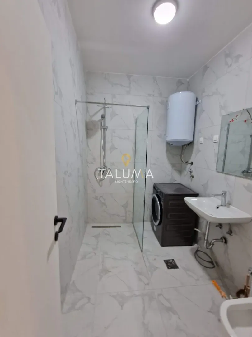 Modern bathroom with a walk-in shower, washbasin, and washing machine.