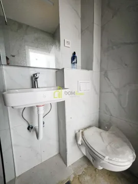 Newly equipped bathroom with a washbasin and toilet bowl clad in marble tiles. - image 2
