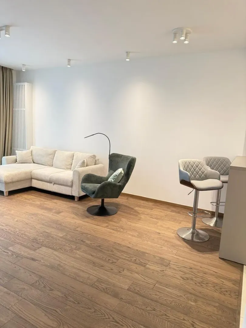 Living room with a sectional sofa, armchair, and a bar with bar stools.