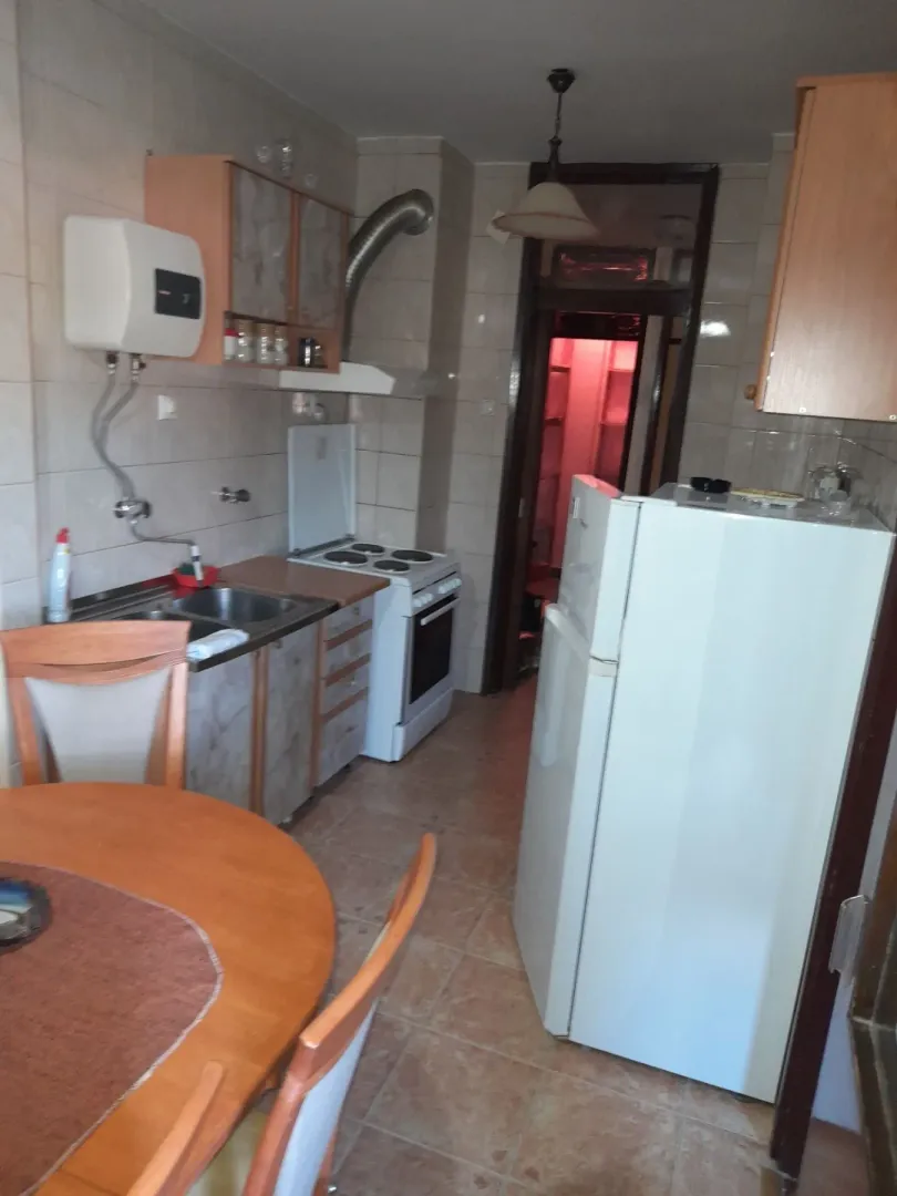 Praktična kuhinja sa trpezarijskim stolom i frižiderom.