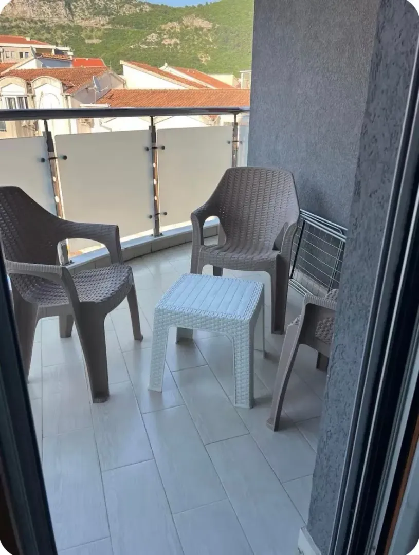 Small furnished balcony with a table and chairs.