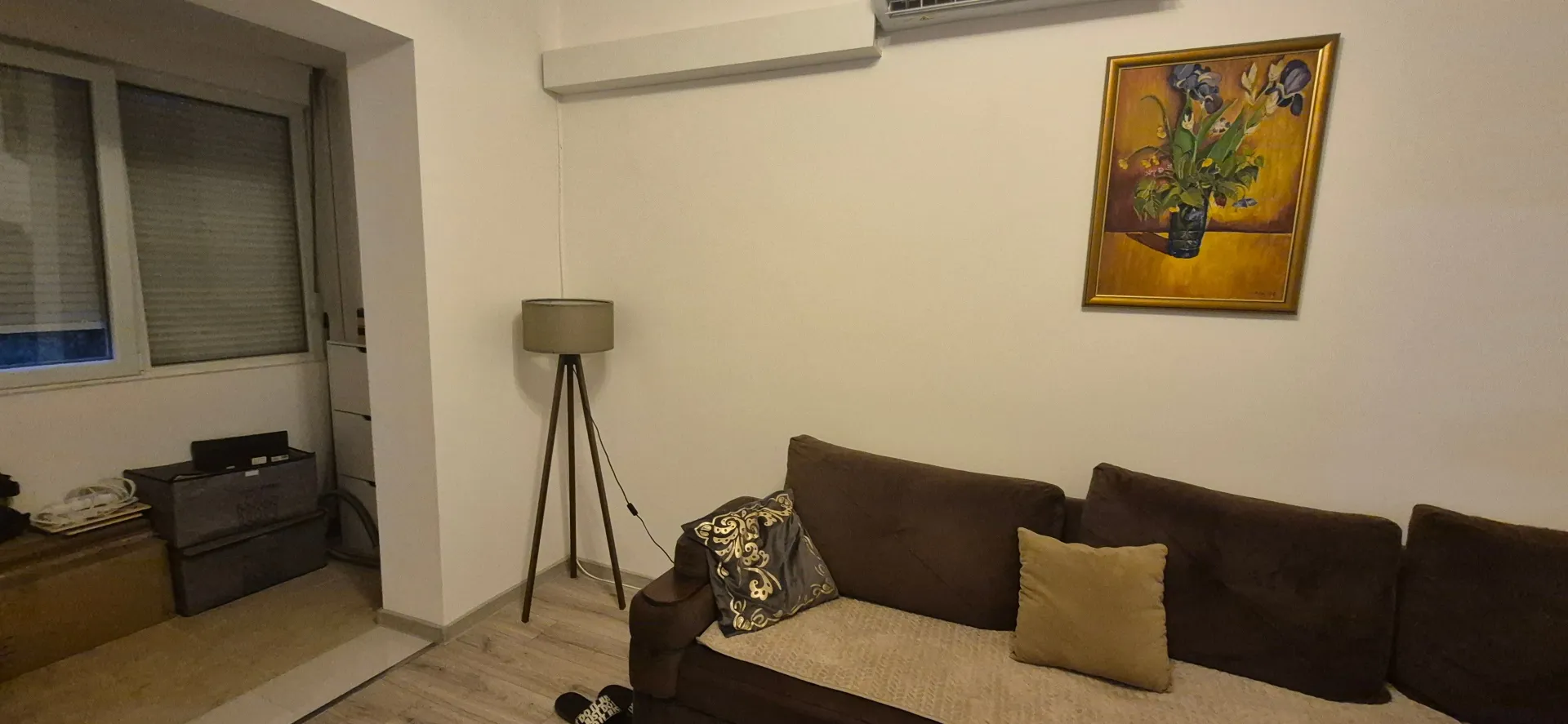 Dnevna soba sa garniturom, podnom lampom i umjetničkom slikom na zidu.