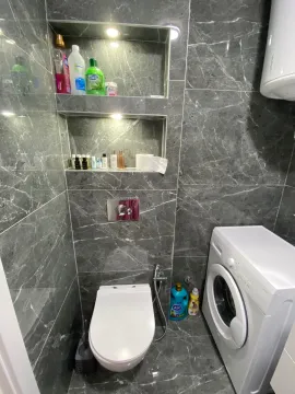 Moderne kupatilo obloženo sivim pločicama sa ugradnom šoljom i veš mašinom. - image 6