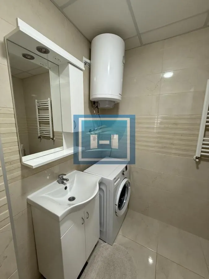 Bathroom with sink, mirror, water heater, and washing machine.