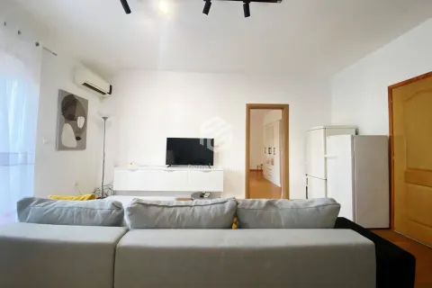 Dnevna soba sa ugaonom garniturom, TV-om i bijelim komadom namještaja. - image 9