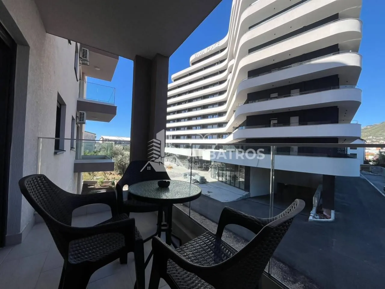 Namješten balkon sa garniturom za sjedenje i pogledom na zgradu.