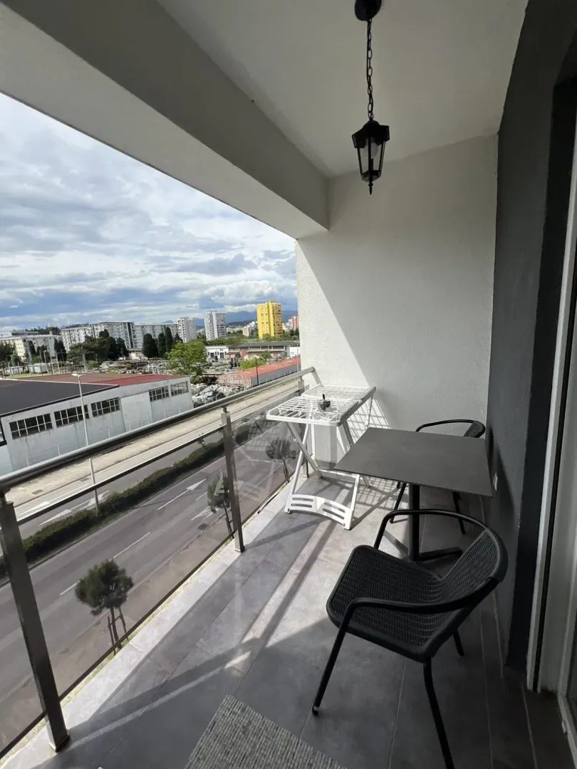 A balcony with a table, chairs, and a view of the city.