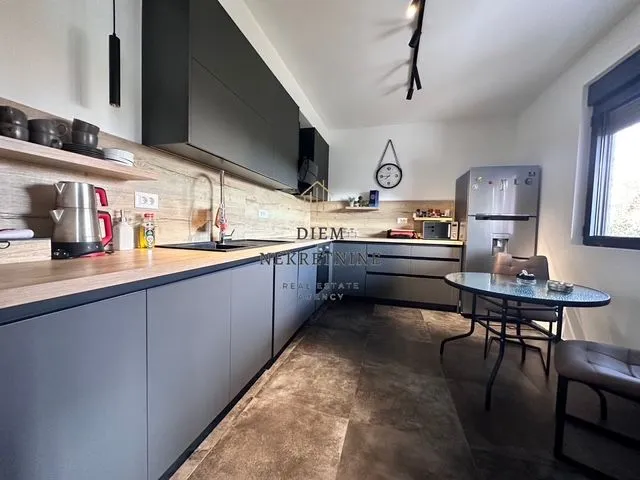 Modern kitchen with a dining table and dark cabinetry.