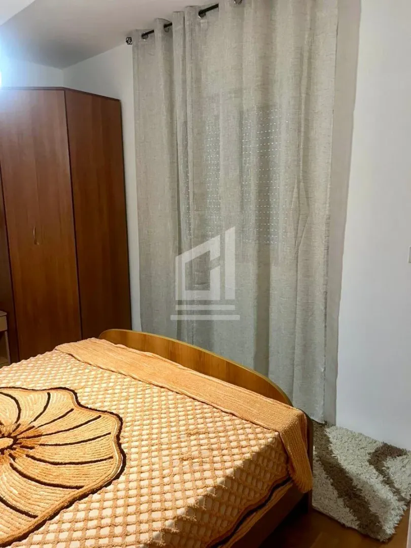 Bedroom with a bed, wardrobe, and a window with curtains.
