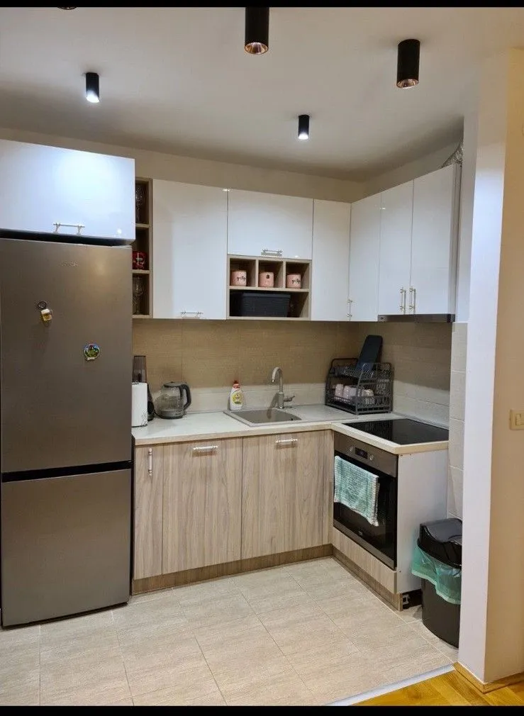 Kitchen with white and wooden cabinets, a refrigerator, and a built-in oven.