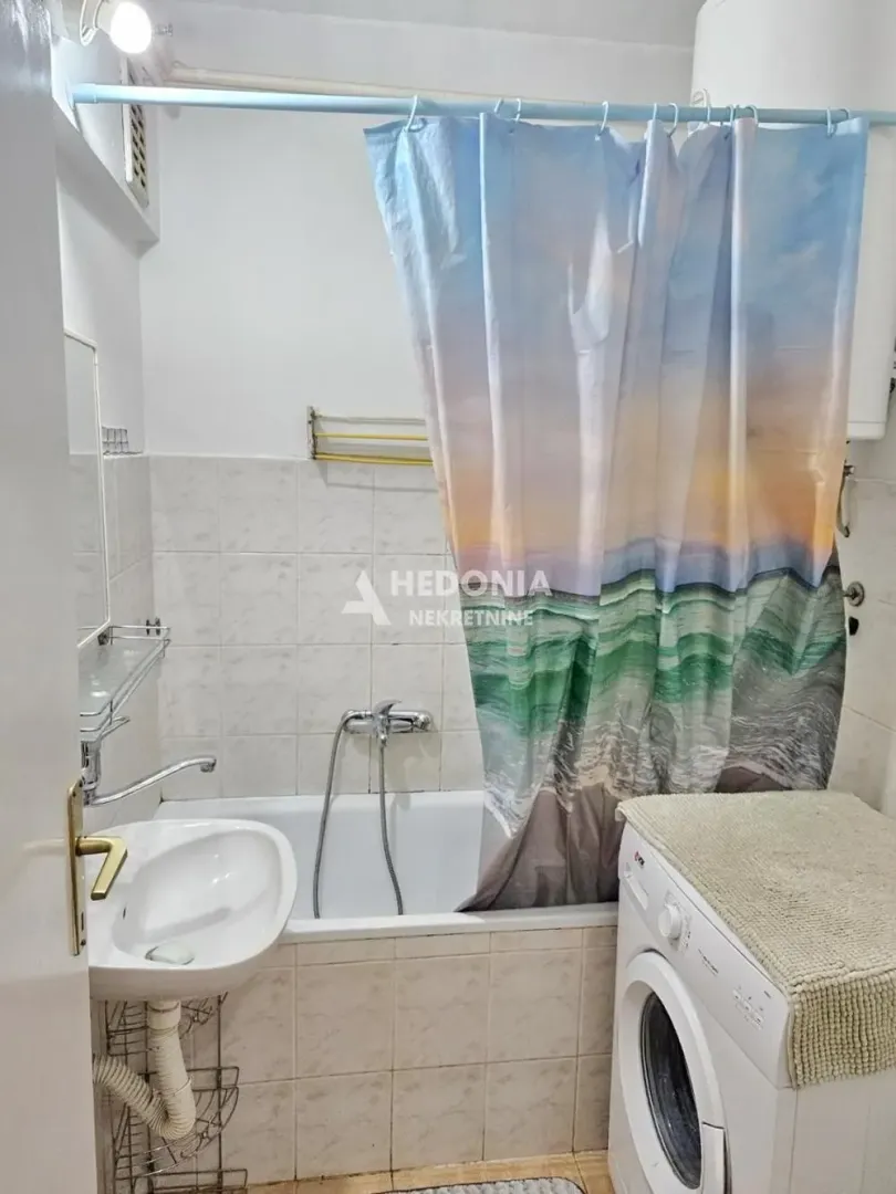 Manje kupatilo sa kadom, umivaonikom i veš mašinom.