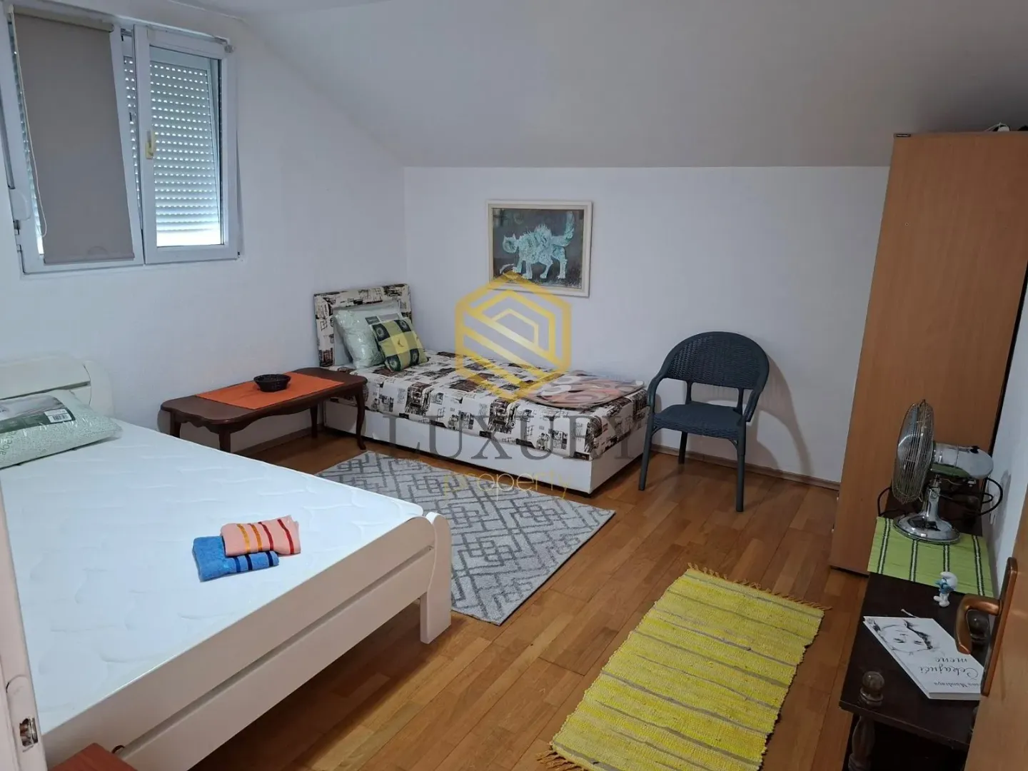 Smaller bedroom with two beds and hardwood flooring.