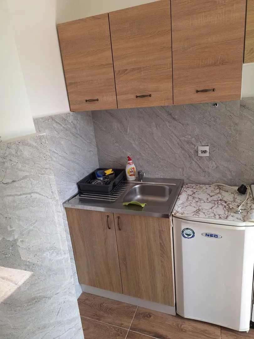 Small kitchen with wooden cabinets, a sink, and a small refrigerator.