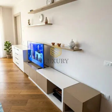 Living room with a TV, console unit, and wall shelves. - image 5