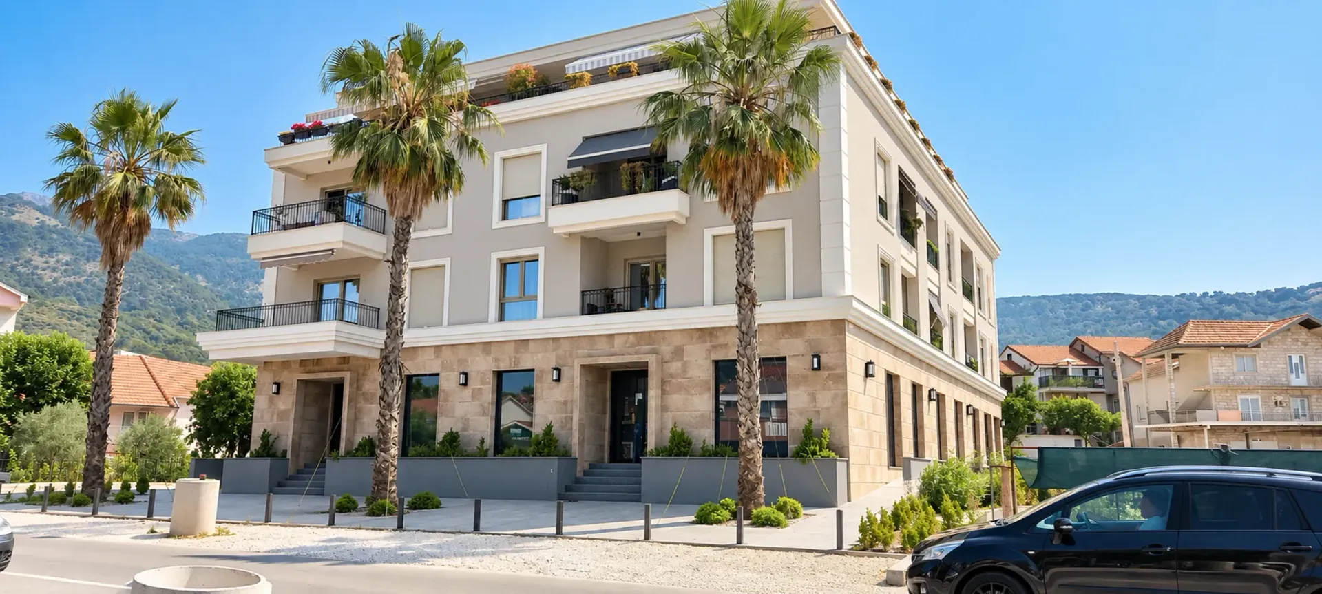 Exterior of a modern residential building with palm trees and a landscaped yard.