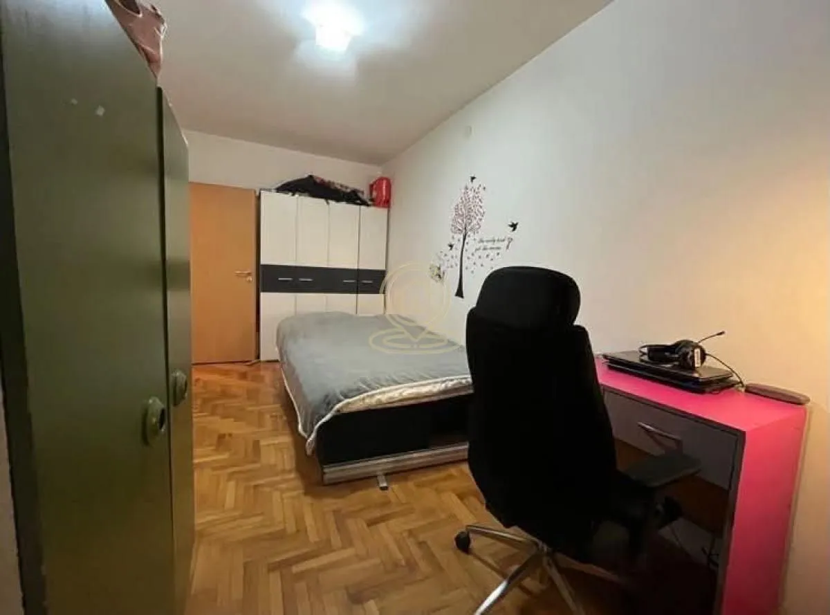 Nameštena spavaća soba sa krevetom, radnim stolom i ormarima.