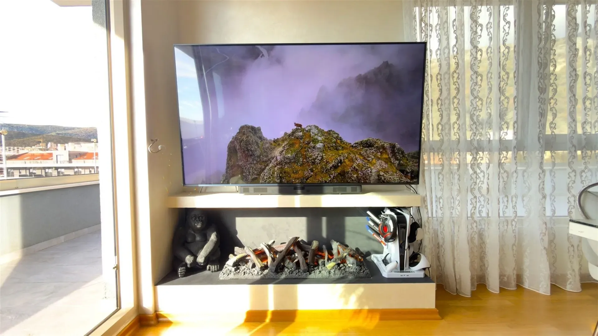 Svijetao dio dnevne sobe sa televizorom i dekorativnim kaminom.