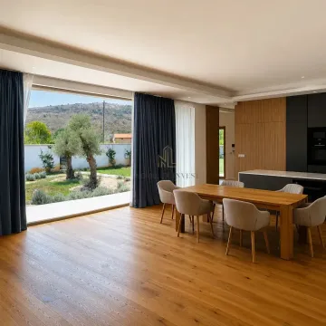 Spacious living room with dining area, wooden flooring and large window overlooking the yard. - image 5