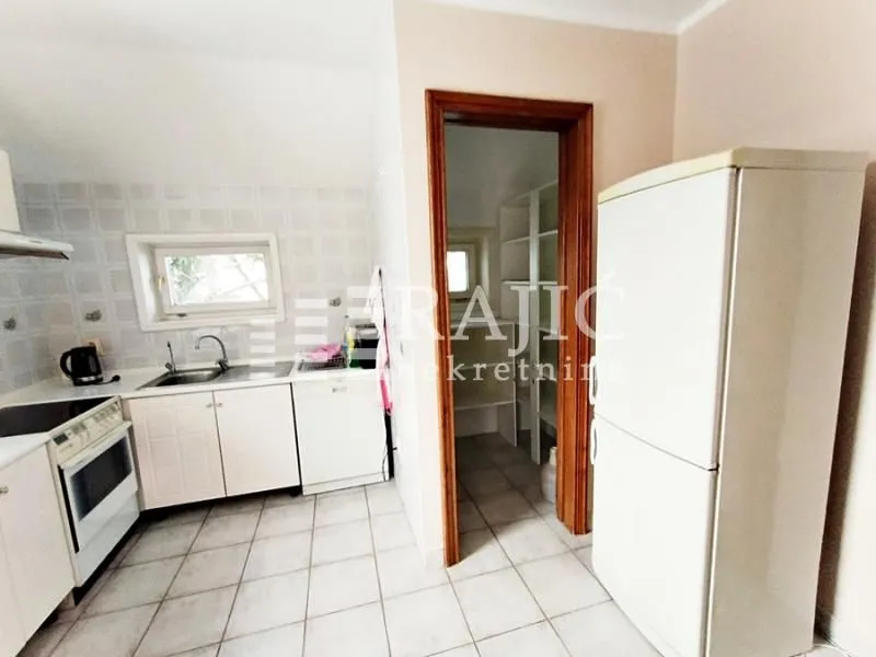 Small bright kitchen with white units and a refrigerator.