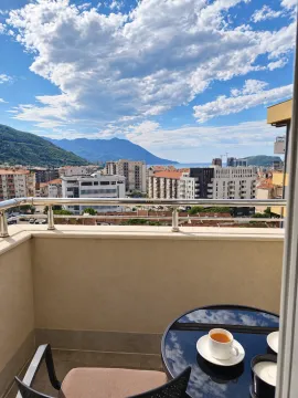 Balcony with a table and a view of the city and mountains. - image 7