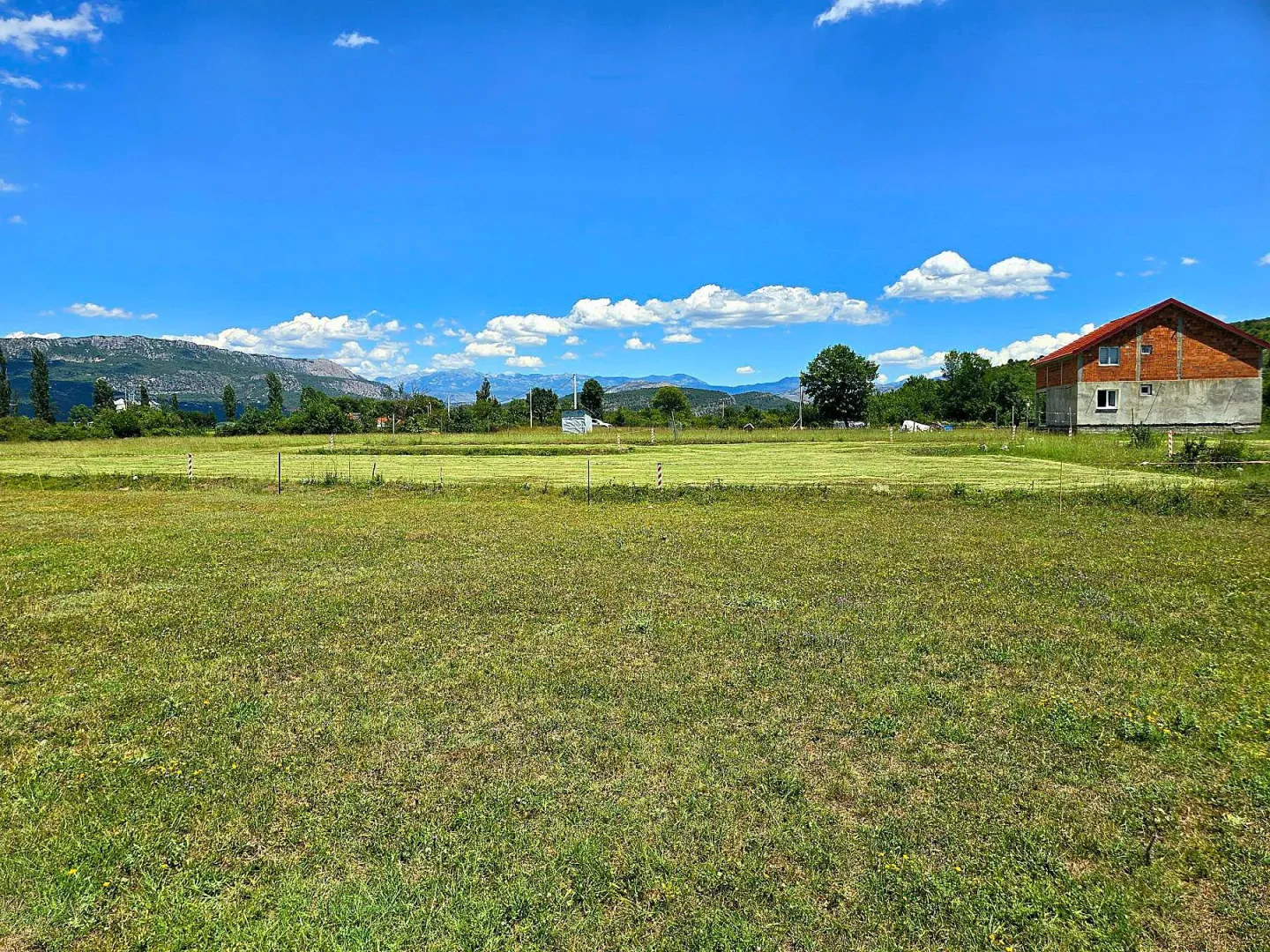 Prostrano travnato zemljište sa pogledom na planine i okolnu prirodu.