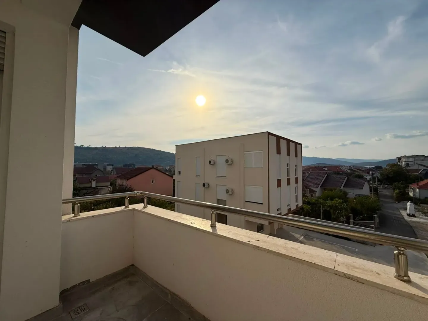 Pogled sa balkona na okolne zgrade i brda.