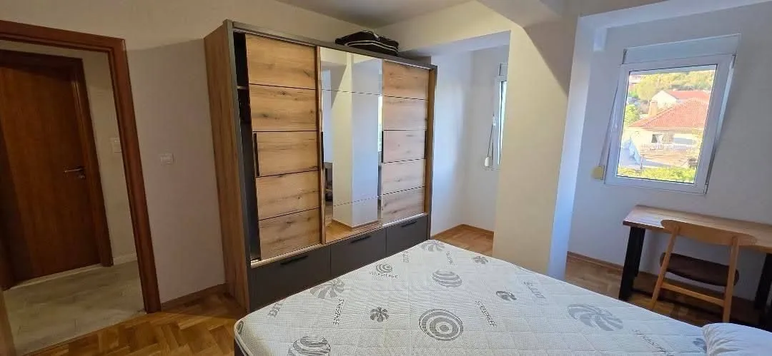 Namještena spavaća soba sa bračnim krevetom, garderoberom i radnim stolom.