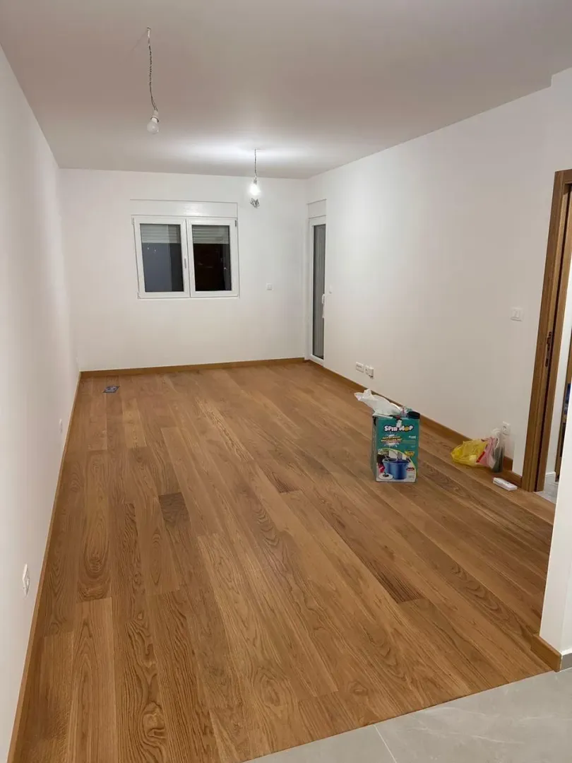 An empty room with wooden flooring and white walls.