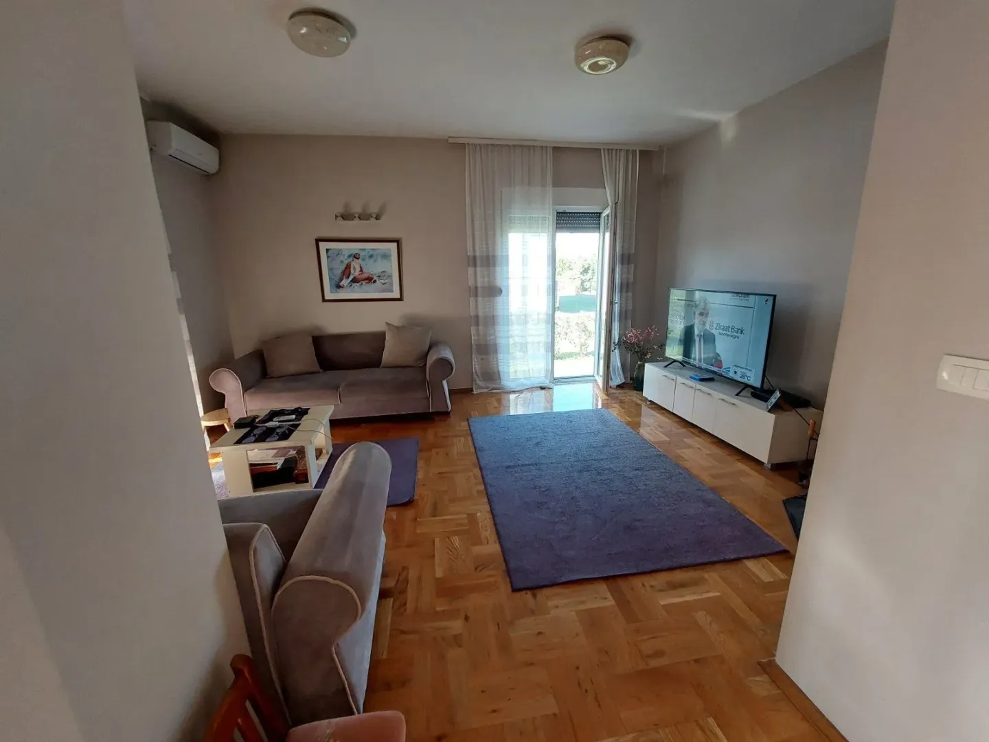 Bright living room with a seating set, TV, and access to the balcony.